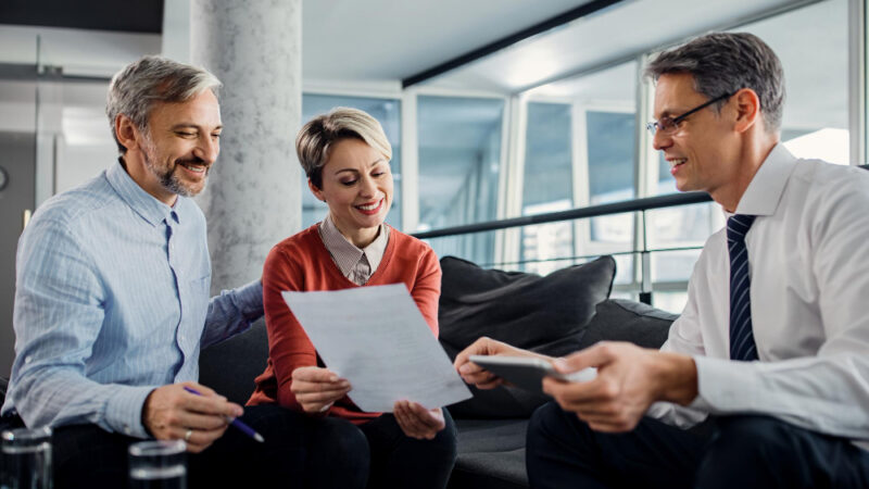 Happy couple and financial advisor going through plans during the meeting