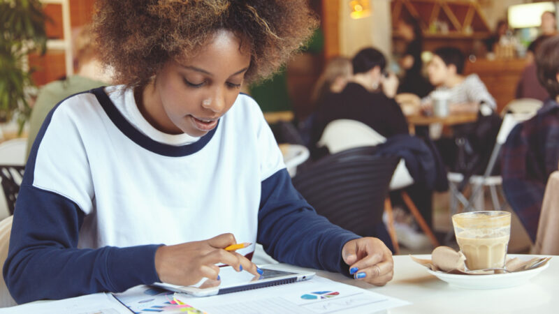 Young woman with curly hair using tablet in cafe