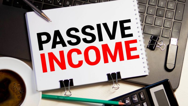 Passive income concept with notebook labeled “Passive Income” on a desk with calculator, coffee, and pen, illustrating dividend investing for beginners and building steady income streams.