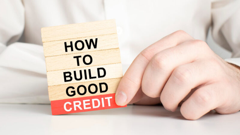 Build good credit symbol wooden blocks with words how to build good credit light bulb icon businessman hand with pen beautiful blue background copy space business and build good credit concept