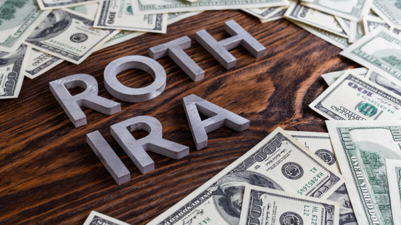 Words roth ira laid on wooden surface by metal letters with us dollar banknotes