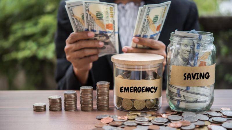 Midsection of businessman counting money with jars and coins on table