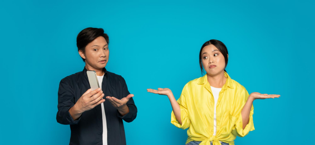 A man showing a smartphone to a perplexed woman both in casual attire
