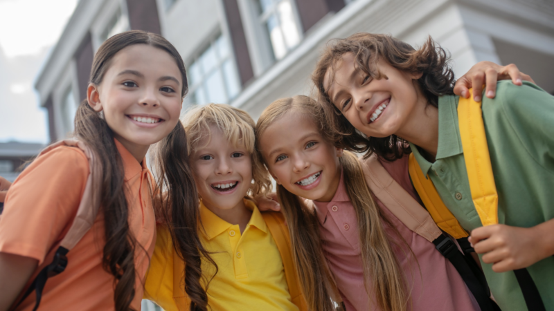 Happy kids. Schoolchildren standing in school yard and looking cheerful